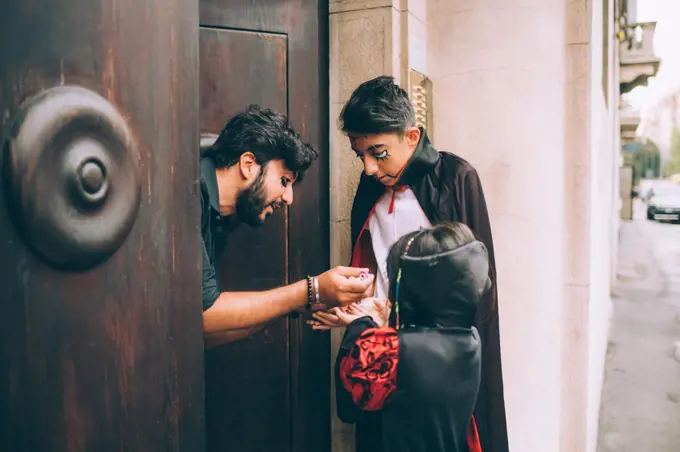 Man giving Halloween candy to children trick or treating 