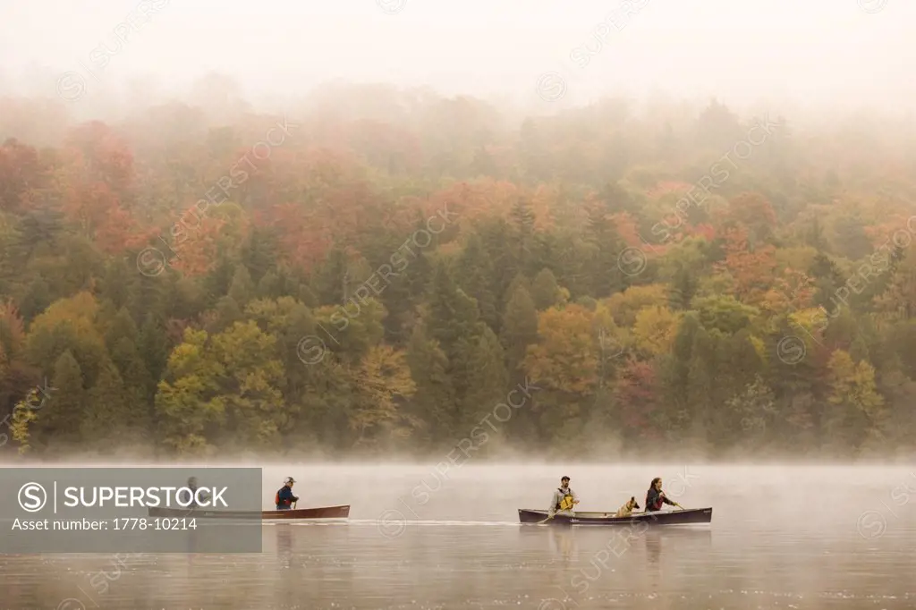 Two young couples canoe on Lake Placid on early autumn morning, Lake Placid, New York, USA