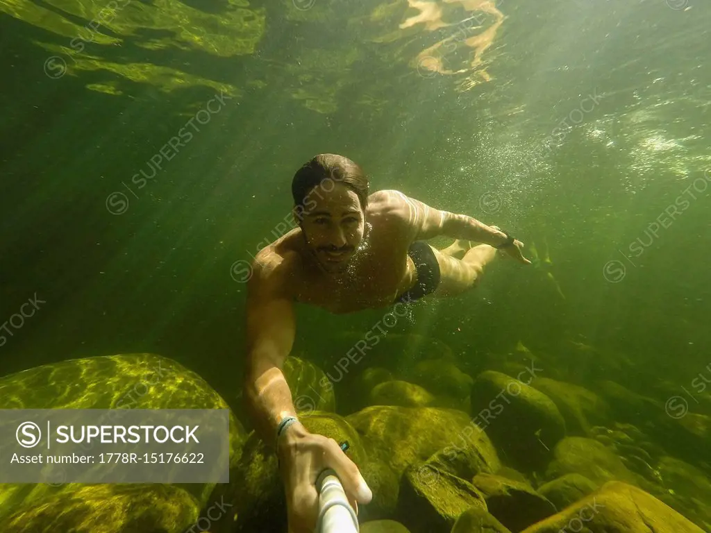 Shirtless man taking underwater selfie in Poco Verde (Green Pool), Guapimirim Sector of Serra dos Orgaos National Park, Rio de Janeiro, Brazil