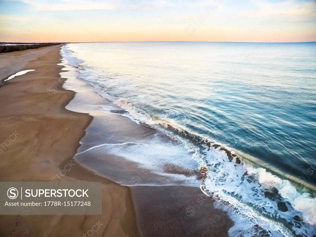 Aerial drone photography over a Rhode Island beach in winter, during sunset