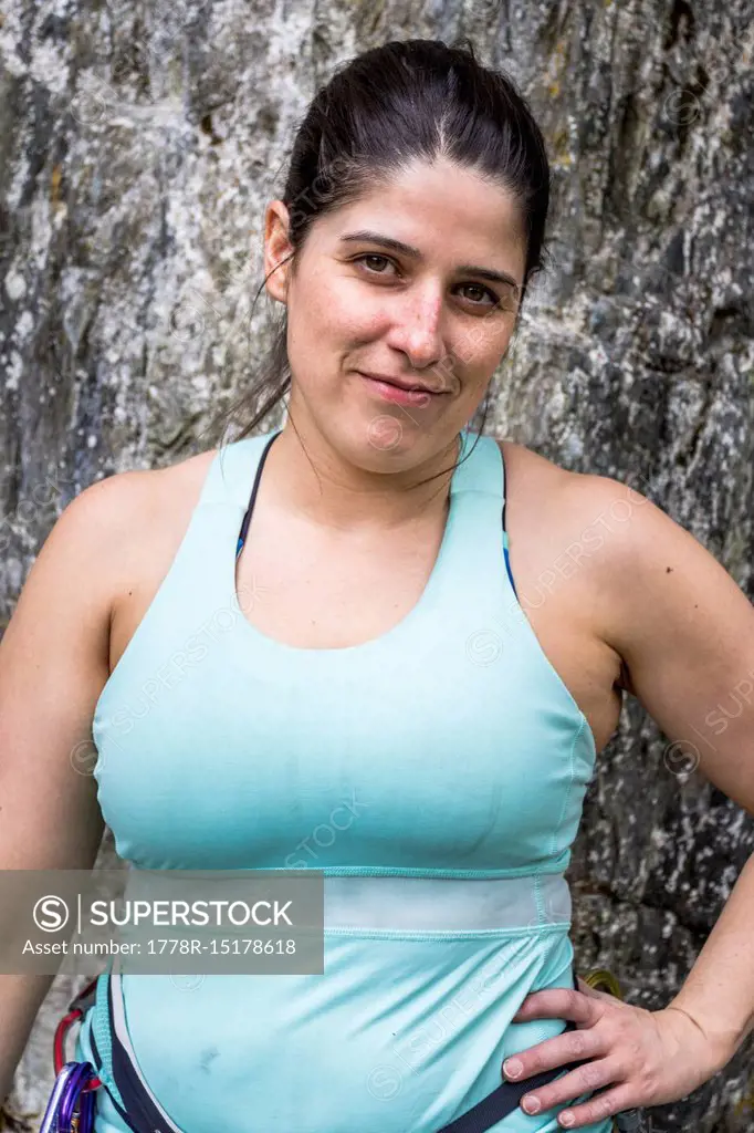 Portrait of female rock climber with black hair and tank top posing for picture with arms akimbo. Whistler, British Columbia, Canada