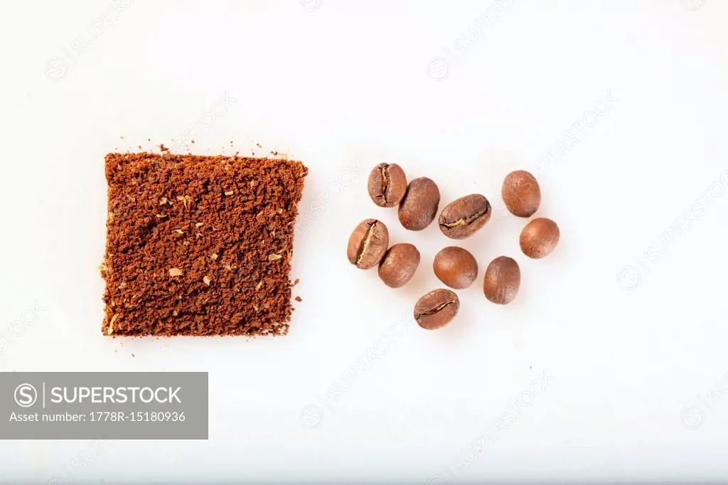 Square of ground coffee and several roasted coffee beans on white background, Oakland, California, USA