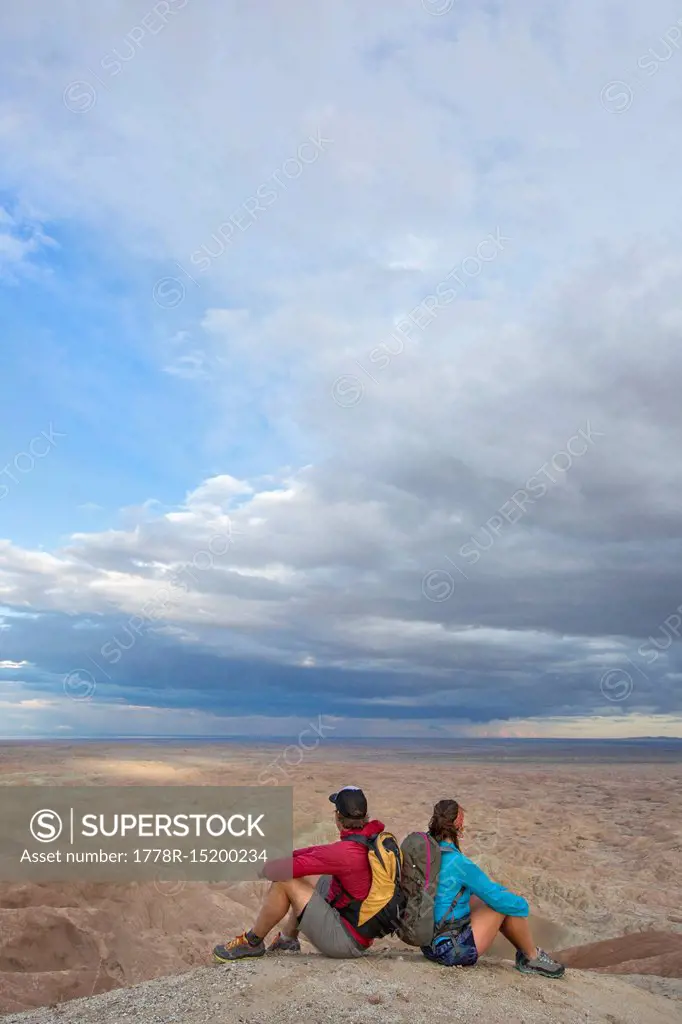 Couple sitting together in badlands section of Anza Borrego State Park and admiring landscape, California, USA