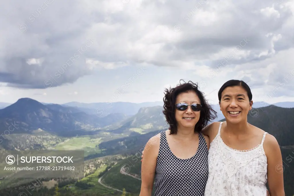 A Japanese American Mother and Daughter stand at Rainbow Curve Overview, with Rocky Mountain National Park stretching out behind them.