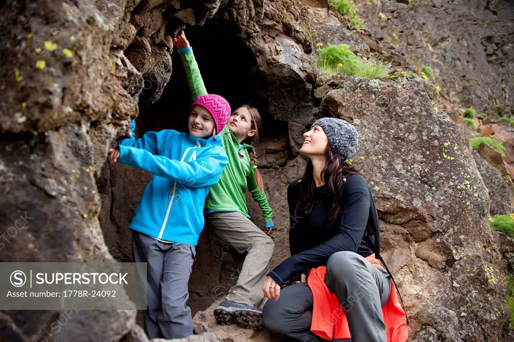 Two daughters and their mother exploring a cave.