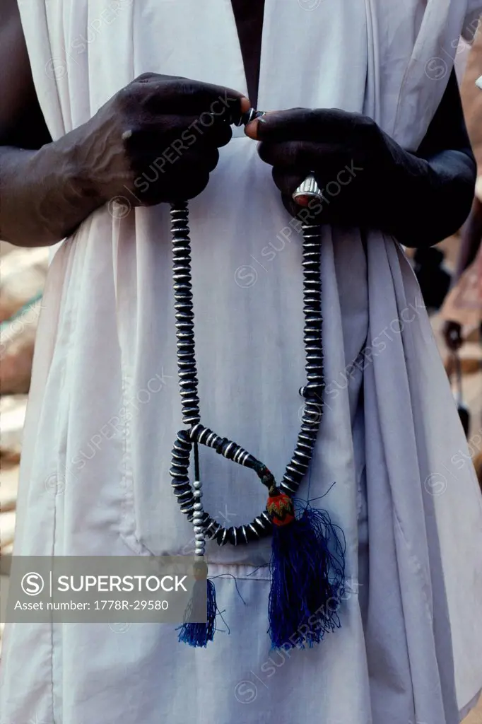 A tribesman holding prayer beads with both hands, Africa.