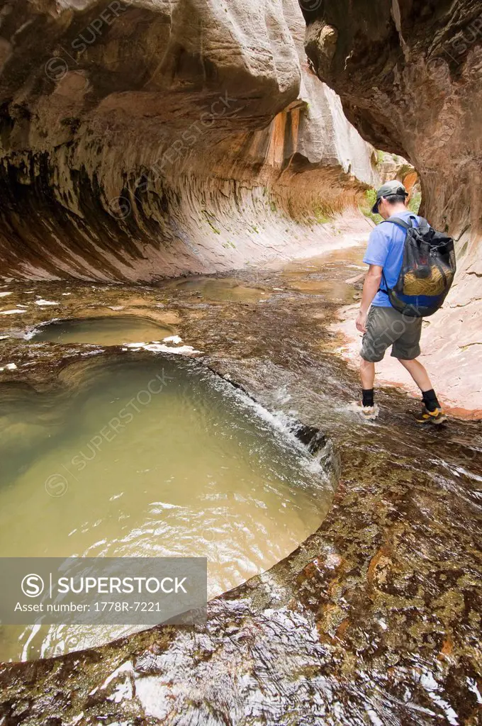 An Asian man hiking next to pools while canyoneering, Zion National Park, Springdale, Utah.