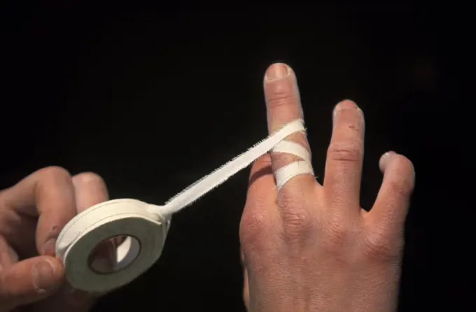 A female athlete taping her hands before rock climbing