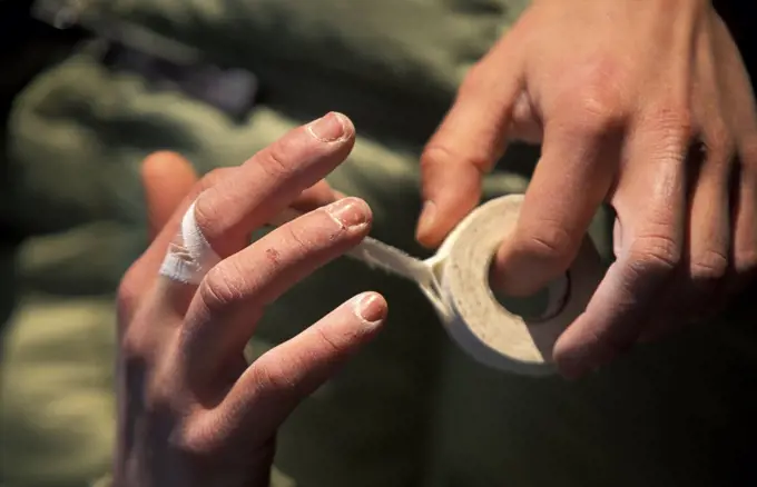 A female athlete taping her hands before rock climbing