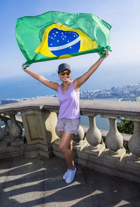 Woman holding Brazilian flag above Rio de Janeiro