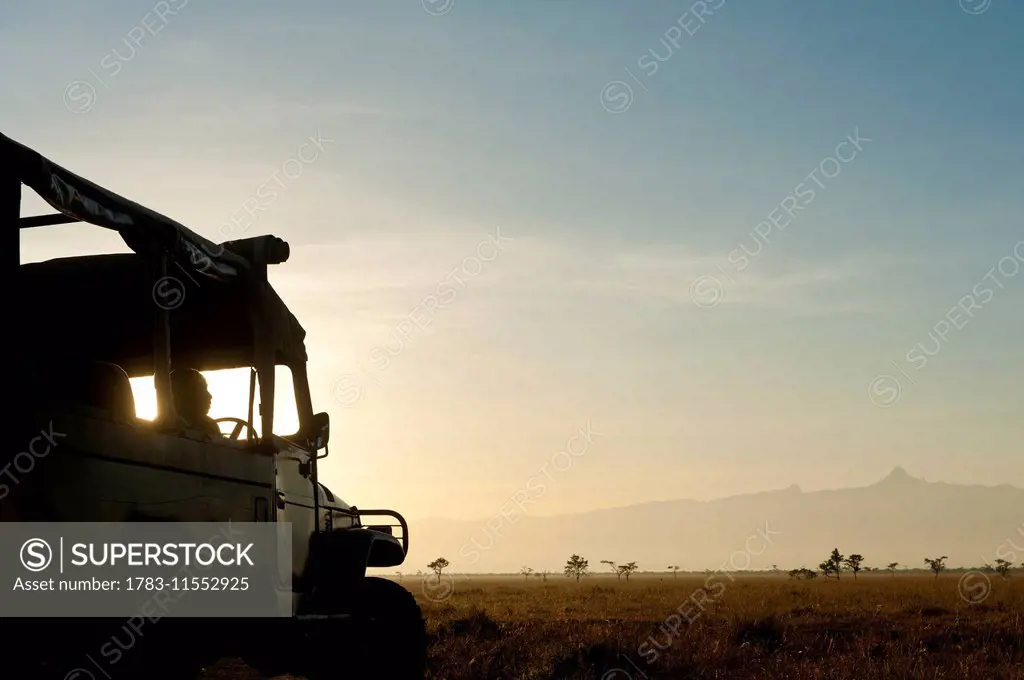 Silhouette of driver in 4x4 in front of Mt Kenya at dawn, Ol Pejeta Conservancy; Kenya