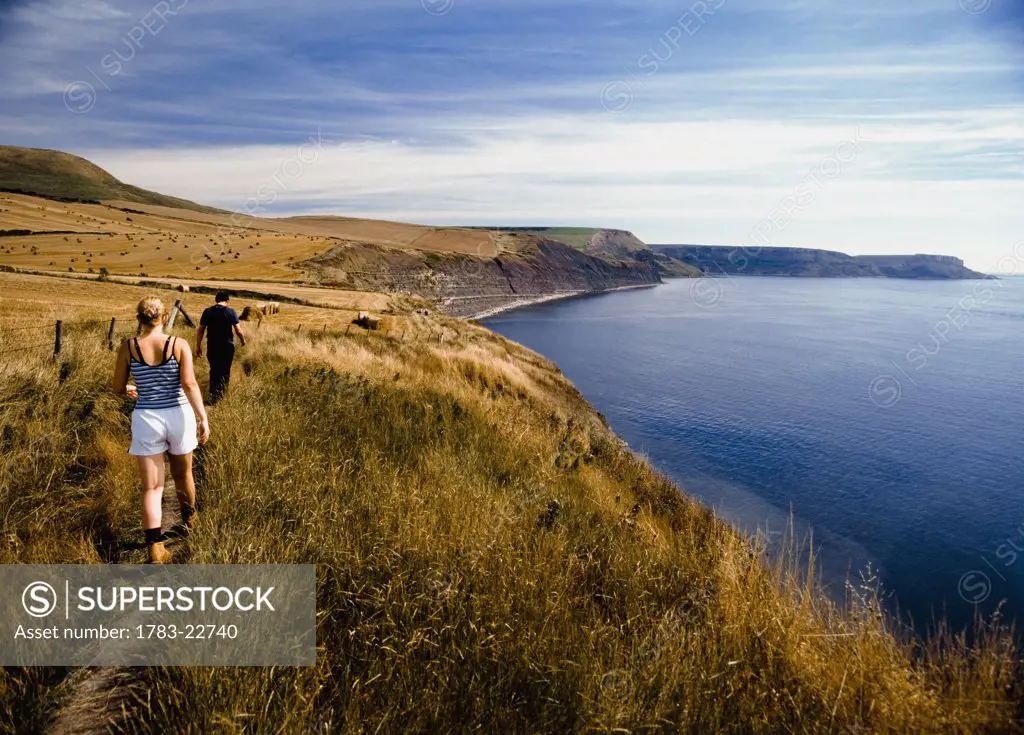 Cauple walking along coastal path, rear view, Purbeck, Dorset, UK.