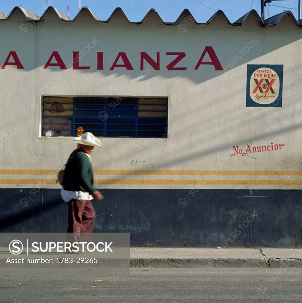 Man passing bar with guitar, Oaxaca, Mexico