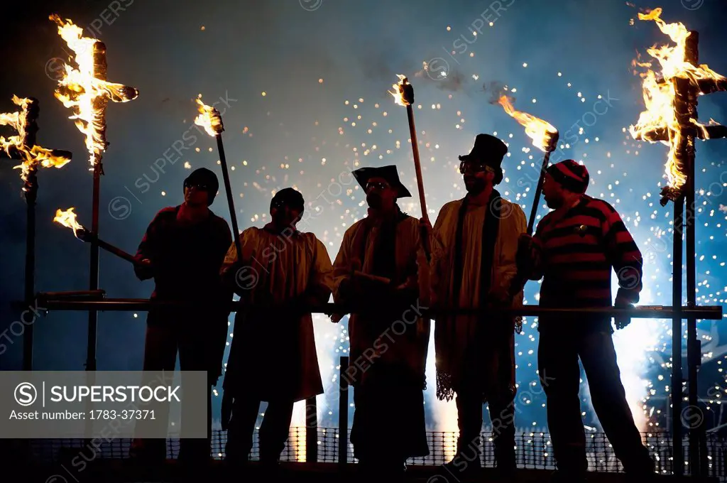 People dressed as clergy on stand with fireworks behind them at Newick Bonfire Night; East Sussex, England, UK