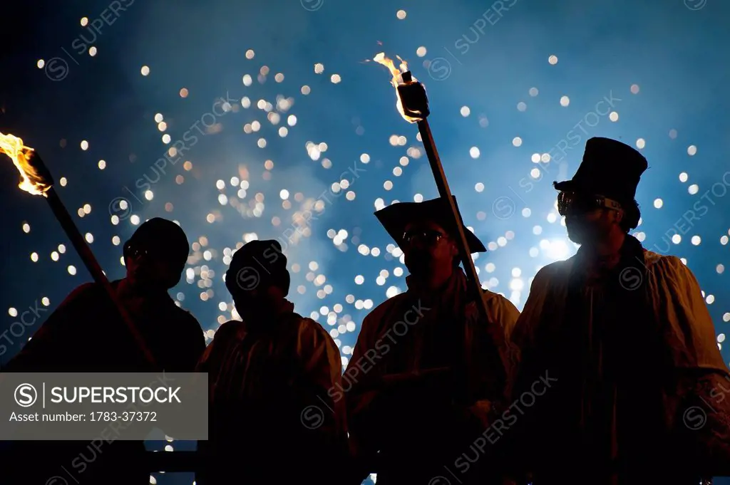 People dressed as clergy on stand with fireworks behind them at Newick Bonfire Night; East Sussex, England, UK