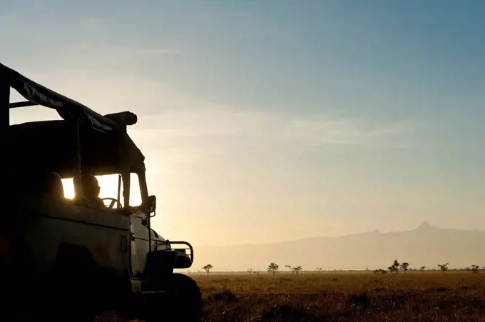 Silhouette of driver in 4x4 in front of Mt Kenya at dawn, Ol Pejeta Conservancy; Kenya