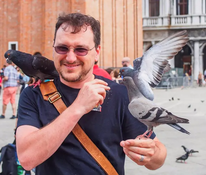 A man feeds the pigeons in Piazza San Marco; Venice, Italy