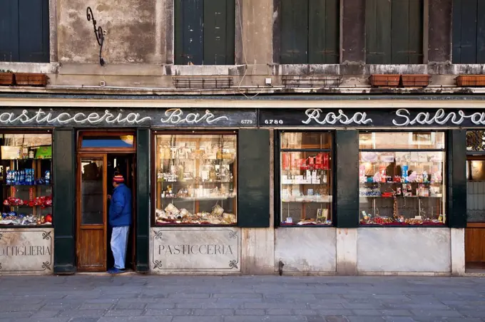 A man standing in the doorway of a retail store; Venice, Italy