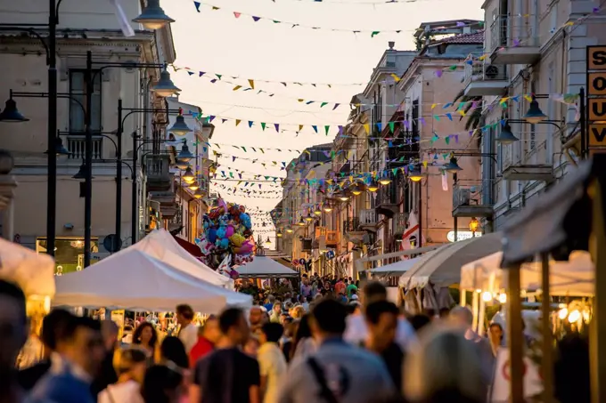 Tourists walking down a busy street at dusk; Olbia, Sardinia, Italy