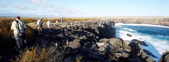 Tourists trekking on rocky cliffs with sea view