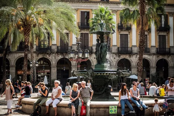 Some tourists sitting in the font of Plaza Real; Barcelona, Catalonia, Spain