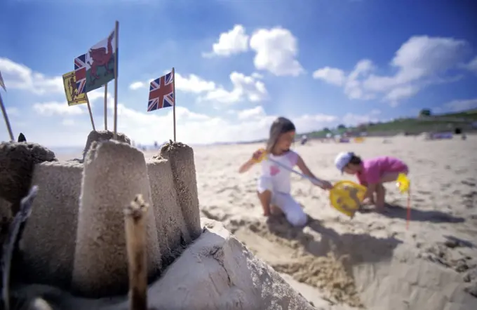 Girls on the beach making a sandcastle, Great Yarmouth, Norfolk, England