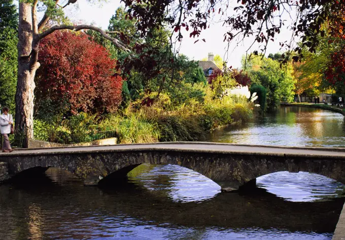 Arched stone foot bridge accros river, Bourton-on-the-Water, Cotswolds, England.