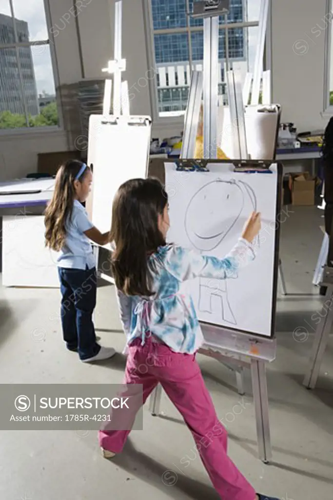 Girls drawing on easels in art class