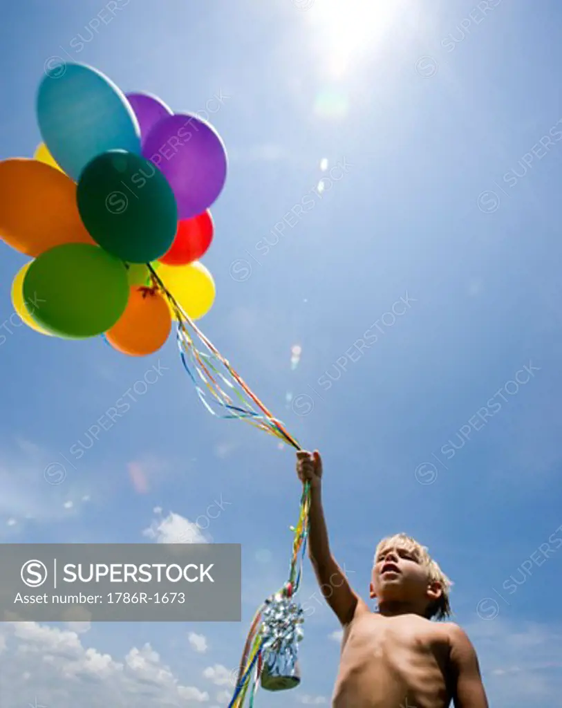 Shirtless boy holding balloons