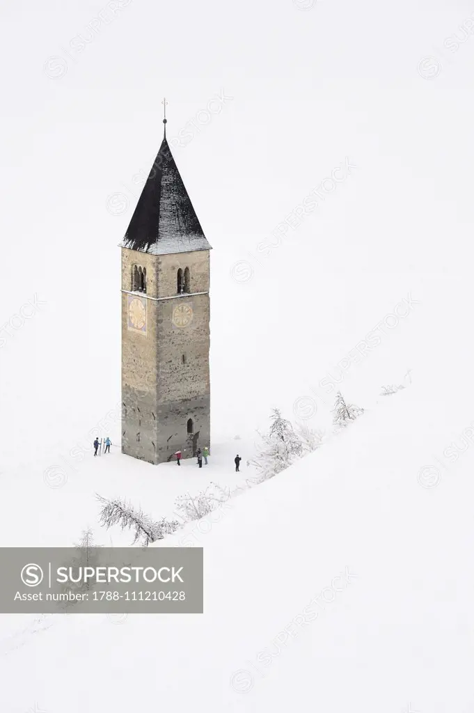 Frozen Lake Resia and bell tower of Saint Catherine's Church, Graun, snowy landscape, Upper Vinschgau Valley, Trentino-Alto Adige, Italy.