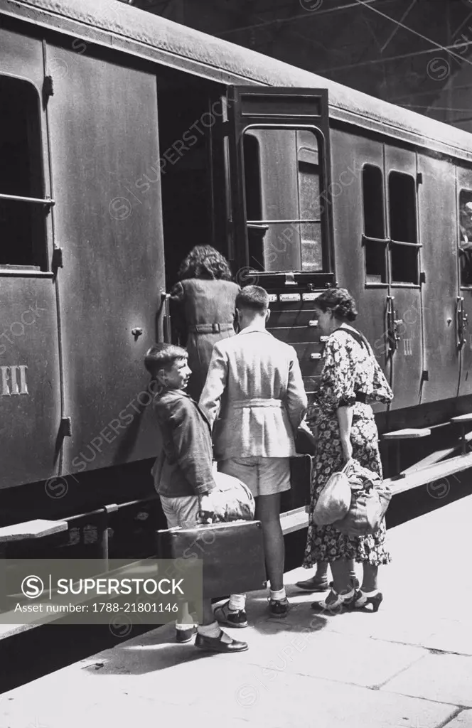 Departure for Ferragosto holidays from Piazza Principe station, a family getting on a third class train carriage, August 14, 1936, Genoa, Italy, 20th century.