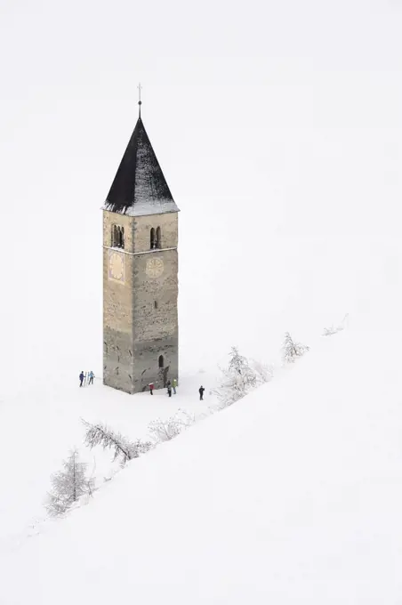 Frozen Lake Resia and bell tower of Saint Catherine's Church, Graun, snowy landscape, Upper Vinschgau Valley, Trentino-Alto Adige, Italy.