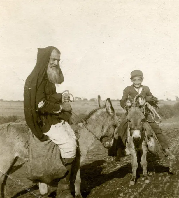 An old man and a boy riding two donkeys, Sardinia, Italy, ca 1910.