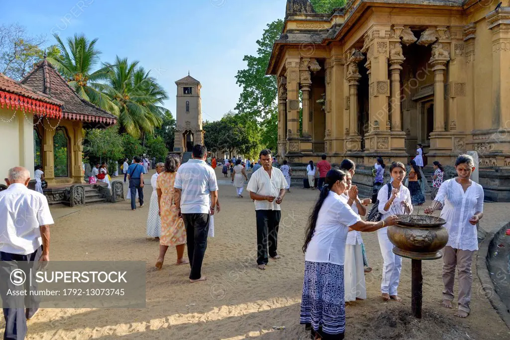 Sri Lanka, Western Province, Colombo District, Kelaniya, Kelaniya Raja Maha Vihara's Buddhist temple, pilgrims in front of a tub with incense with the...