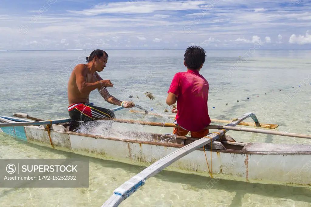 Philippines, Palawan, Roxas, Green Island Bay, Purao Island, father and son fishing in shallow water with fishnet