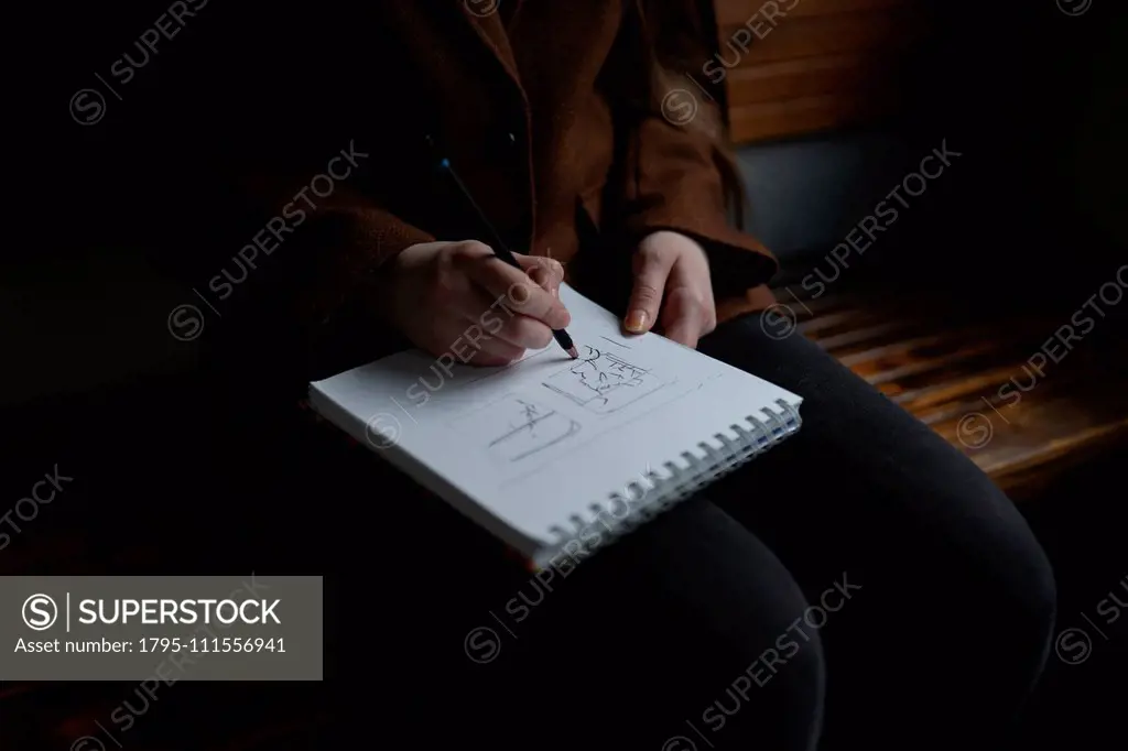 Woman drawing in note pad on train