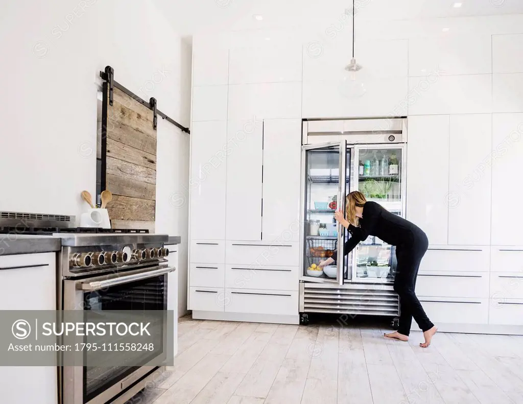 Woman reaching into refrigerator