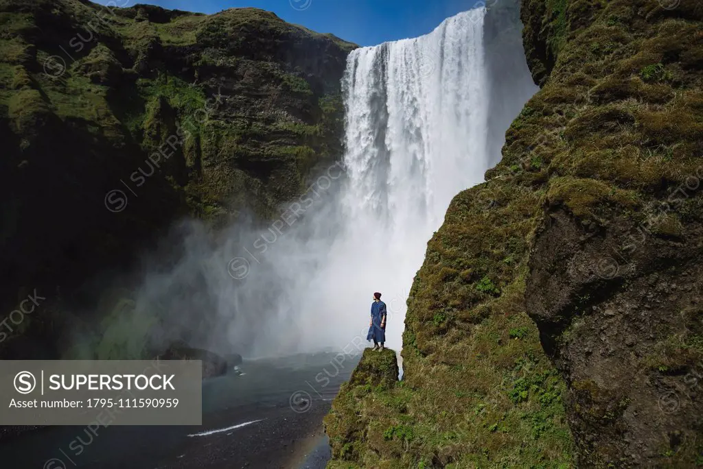 Man standing by Skogafoss waterfall in Iceland