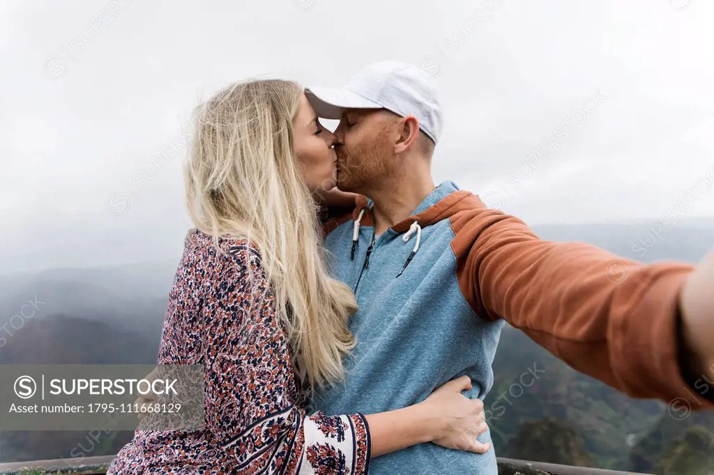 Mid adult couple taking selfie while kissing