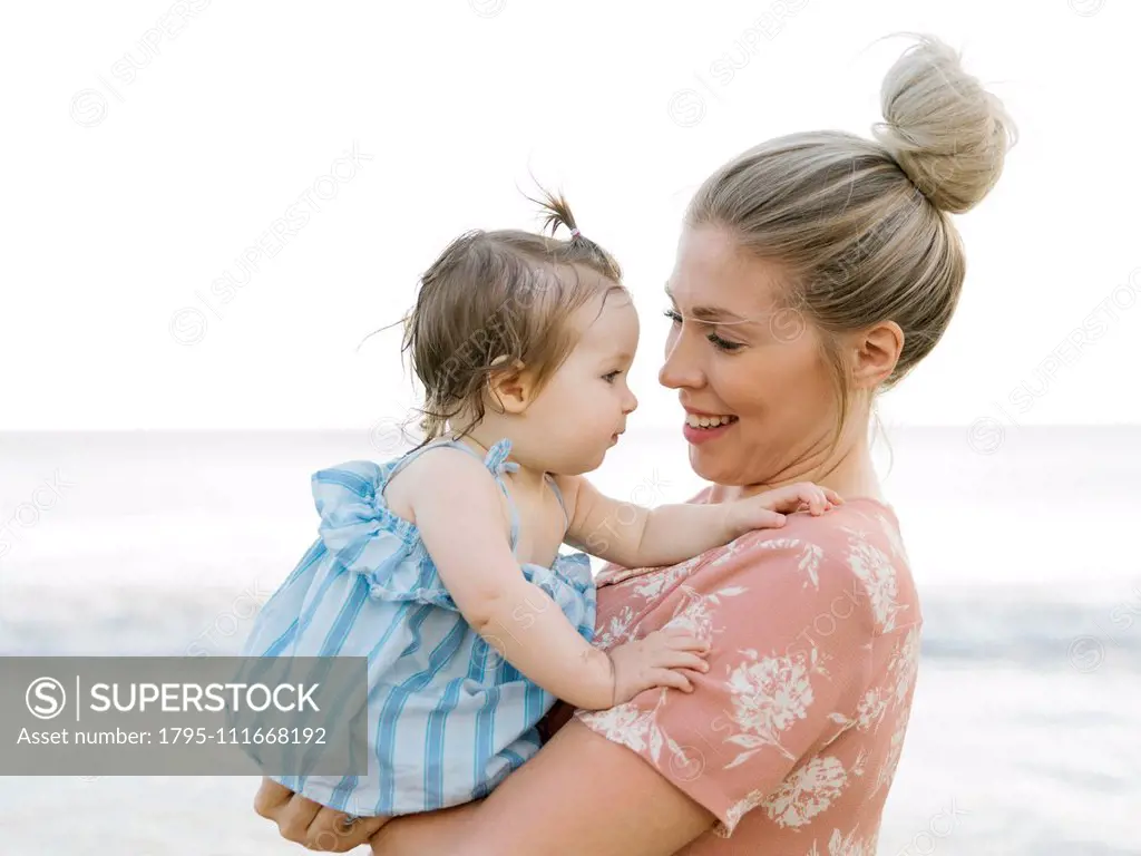 Woman holding baby daughter on beach