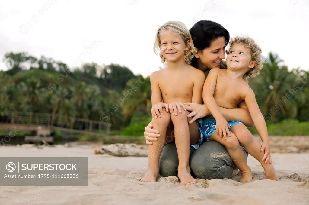 Woman with her sons sitting on her lap on beach