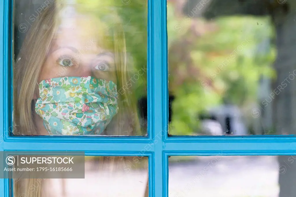 Woman in face mask looking through window