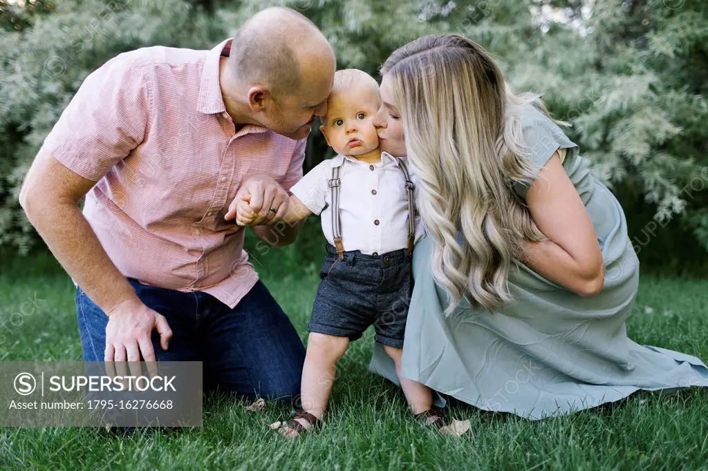 Parents kissing baby son in garden