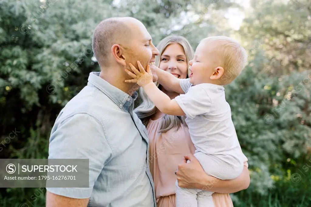 Happy parents standing in garden with baby son