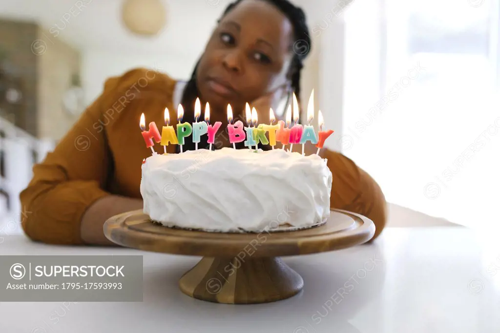 Portrait of woman behind birthday cake