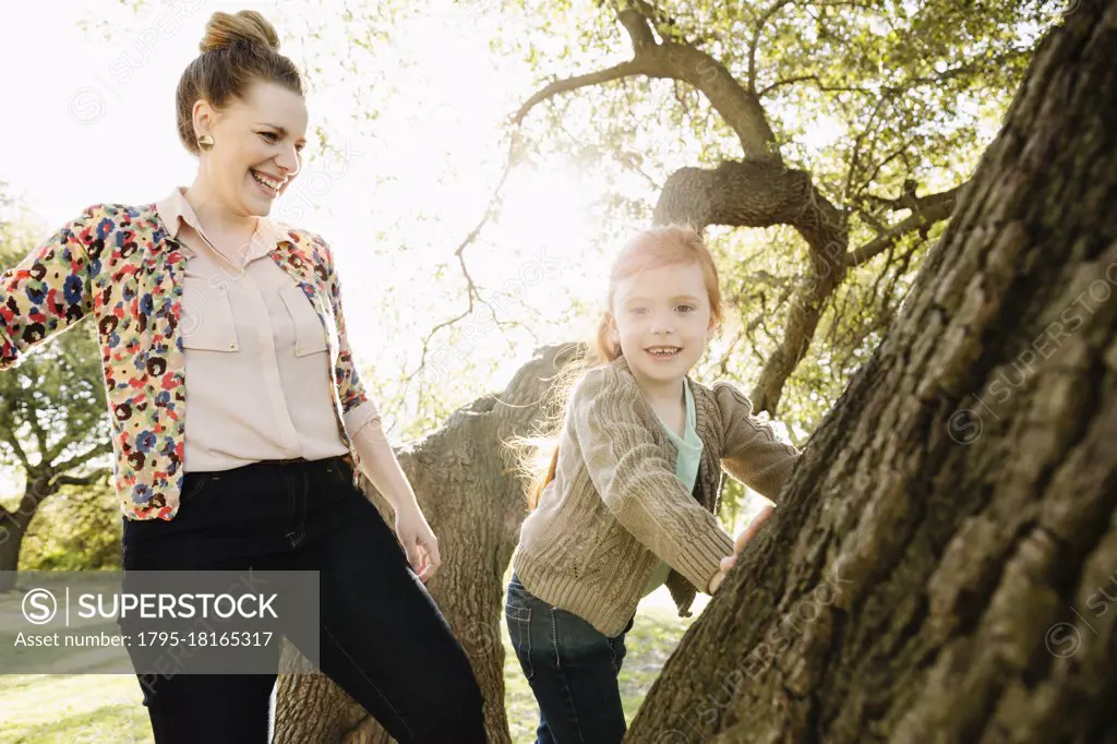 Portrait of mid adult mother watching daughter climb tree