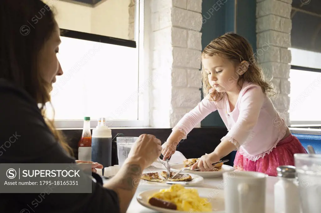 Mother and toddler daughter eating in diner