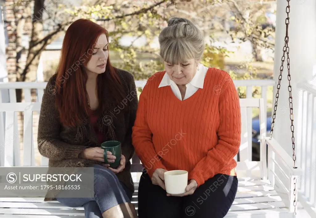 Senior woman and adult daughter having serious discussion on porch