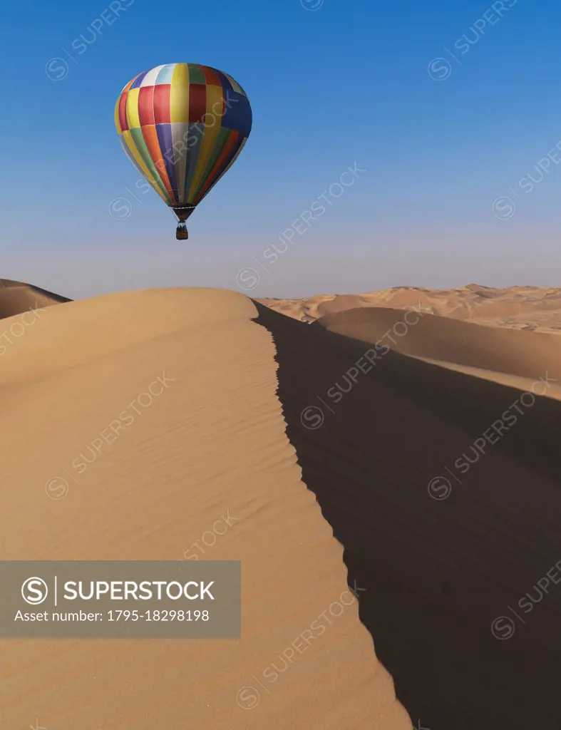 Dubai, United Arab Emirates, Colorful hot air balloon flying over sand dunes