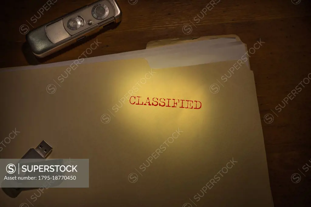 Folder marked Classified with spy camera and thumb drive